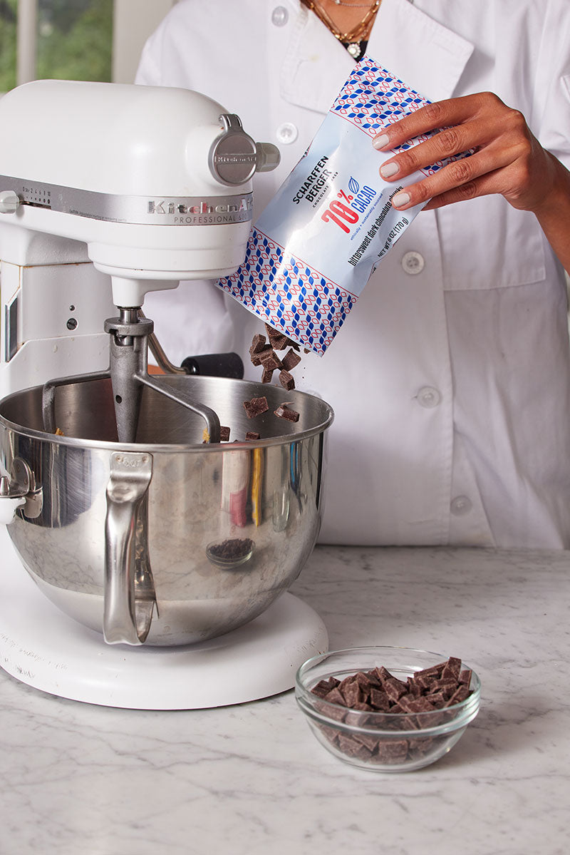 A chef is pouring 70%cacao chunks into a mixer