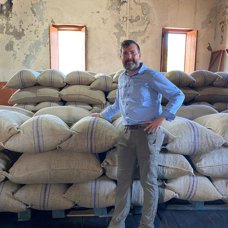 Chris with a warehouse of sacks of cacao